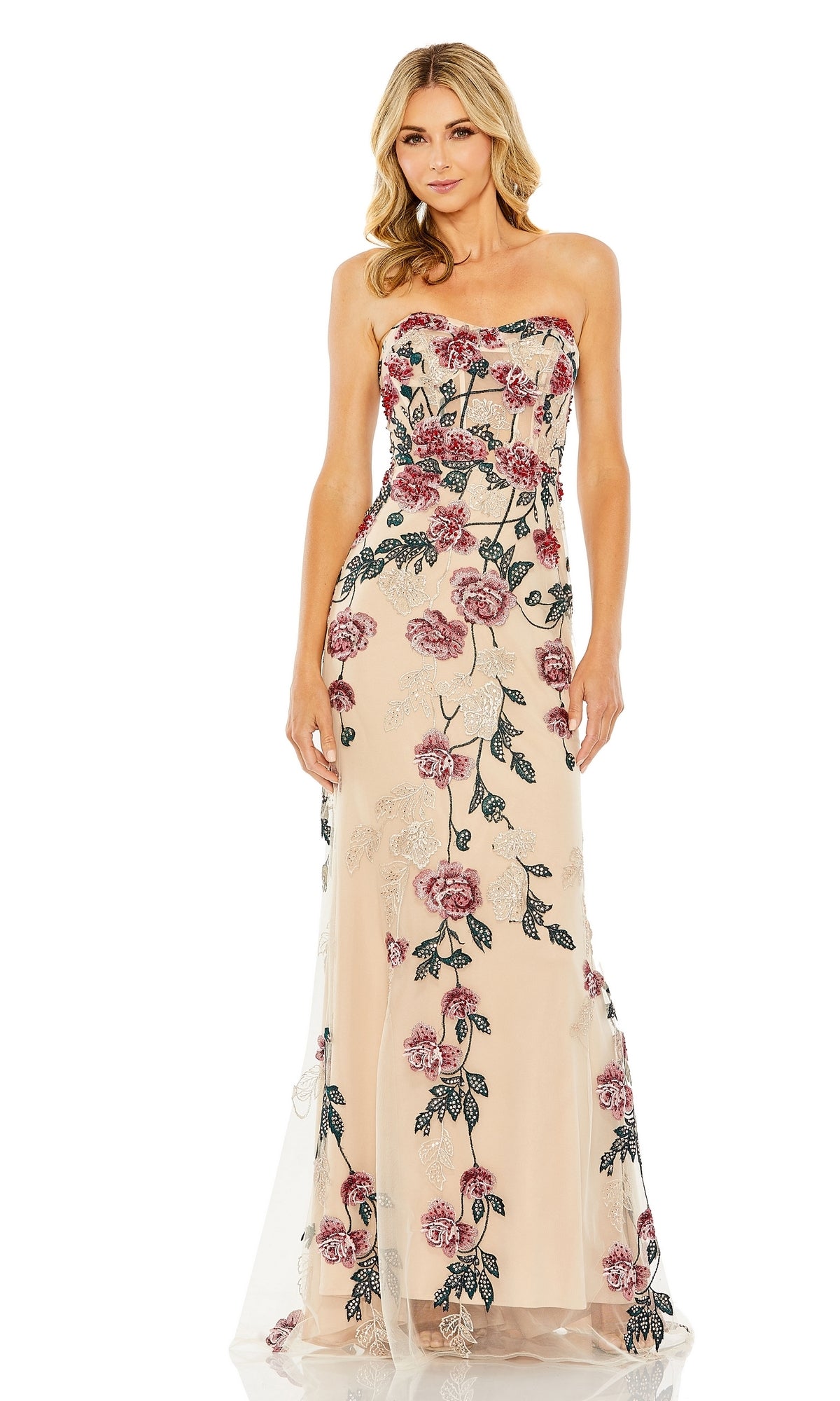 A woman stands against a white background wearing the Long Formal Dress 20581 by Mac Duggal, a strapless, floor-length beige gown with pink and black floral embroidery.